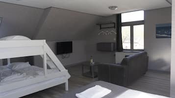 A modern hotel room with a bunk bed, a sofa, a TV, and a window with a view.