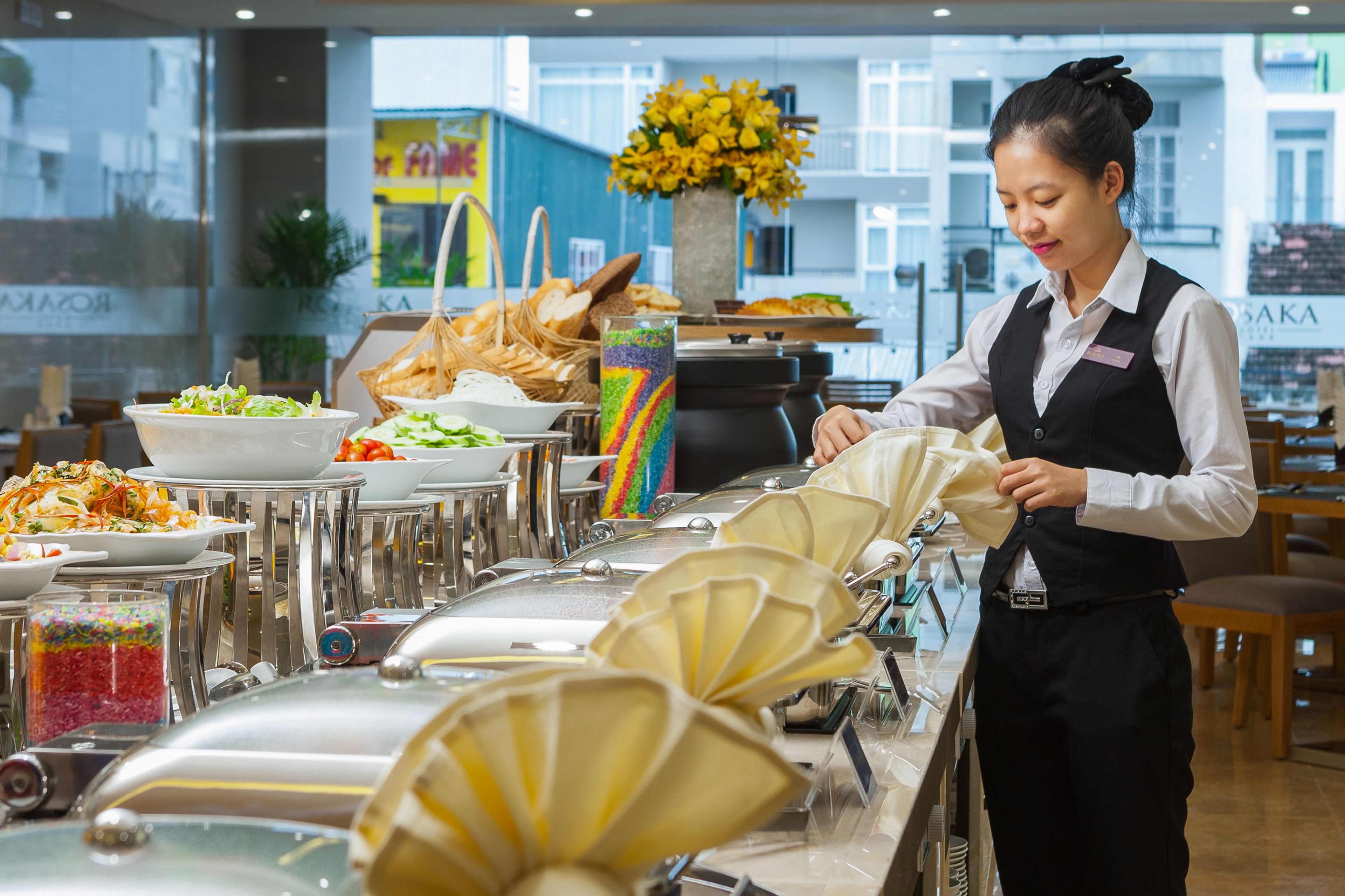 A buffet setup with various food items and a server attending to the buffet line.