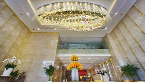 A spacious lobby with a large chandelier, a reception desk, and potted plants. - Rosaka Nha Trang Hotel (Nha Trang)