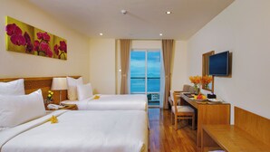 A hotel room with two beds, a desk, a chair, a TV, and a large window with a view. - Rosaka Nha Trang Hotel (Nha Trang)