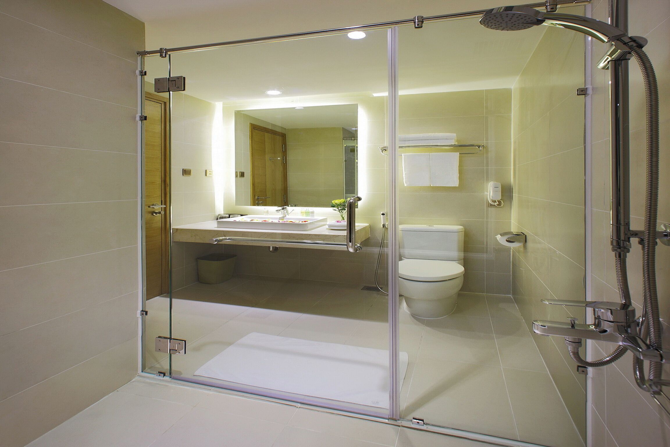 A modern bathroom with a glass-enclosed shower, a visible toilet, and a sink area.