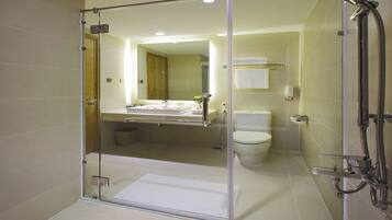 A modern bathroom with a glass-enclosed shower, a visible toilet, and a sink area.