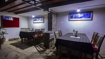 A dining area with a stone wall, wooden chairs, and a table with a striped tablecloth.