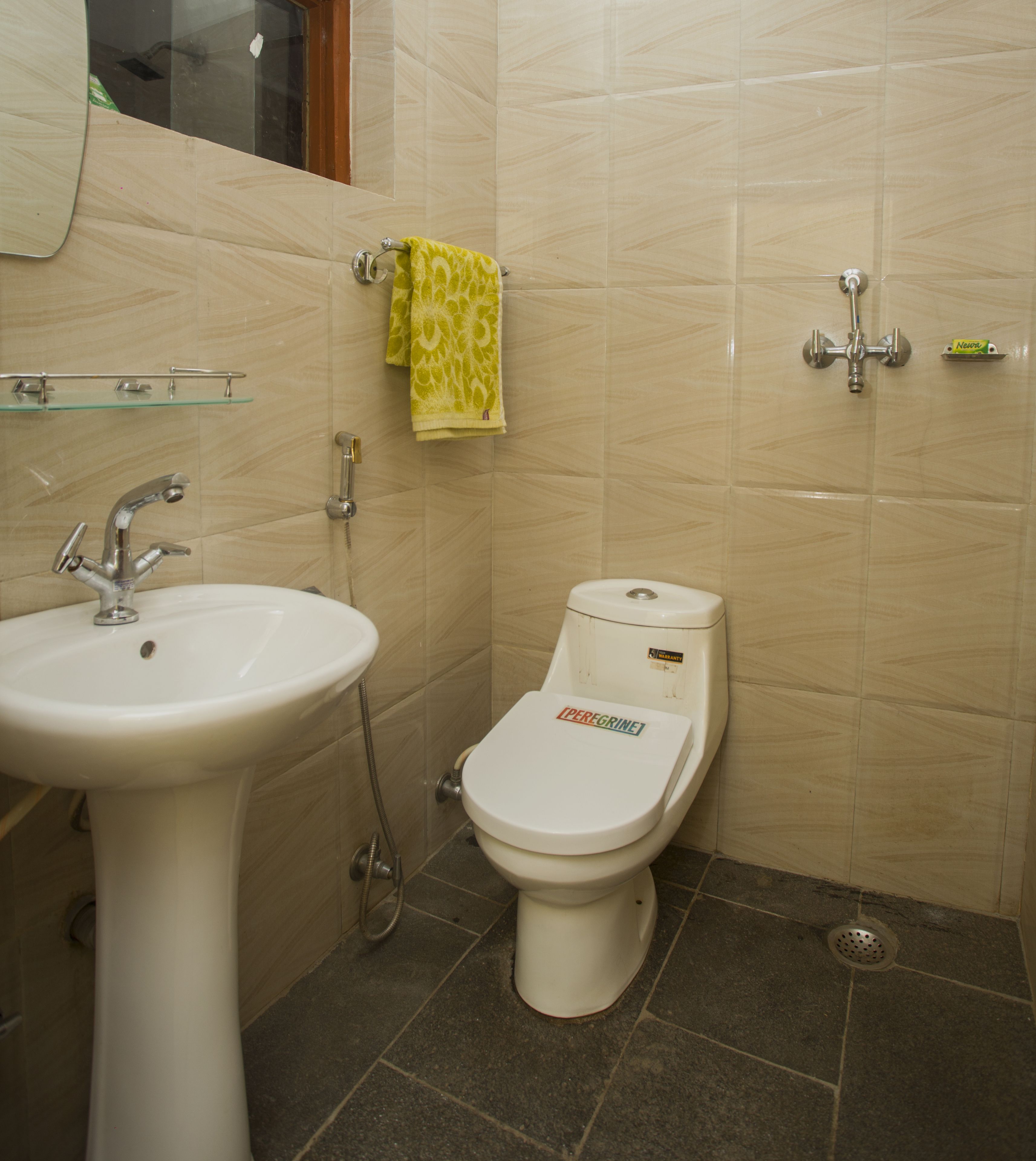 Un baño con un lavamanos blanco, un inodoro y un estante de vidrio.