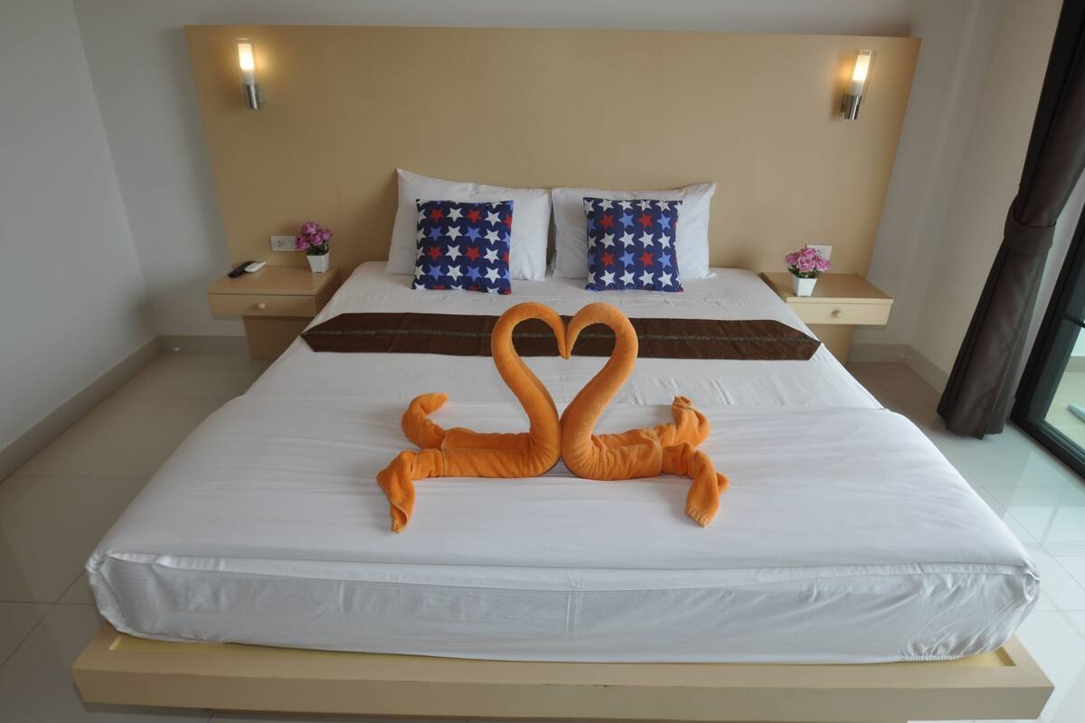 Una habitación de hotel con una cama grande, dos mesitas de noche y una decoración con forma de corazón hecha de toallas.