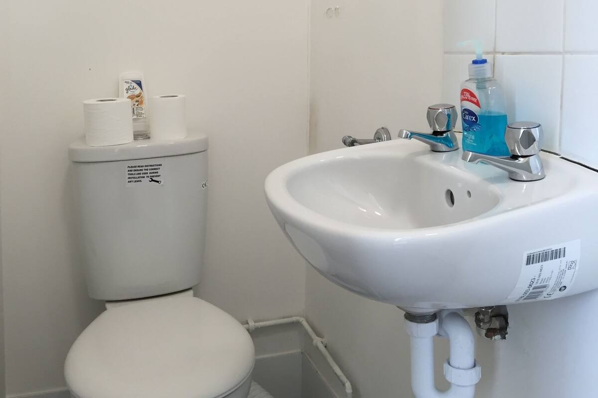 Een badkamer met een wit toilet, een wit wastafel en een spiegel boven de wastafel.