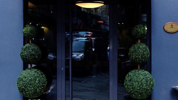 A hotel entrance with a glass door, a clock on the wall, and a street visible through the door. - Vavien Hotel (Istanbul)