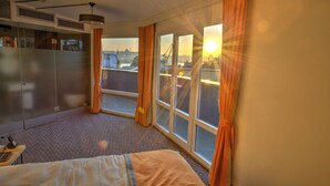 A hotel room with a bed, a wardrobe, a desk with a lamp, and a large window with curtains. - Vavien Hotel (Istanbul)