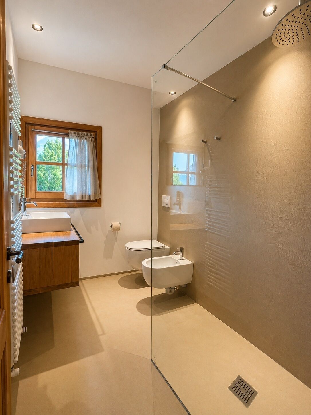 A modern bathroom with a glass shower enclosure, a wooden vanity, a toilet, and a bidet.