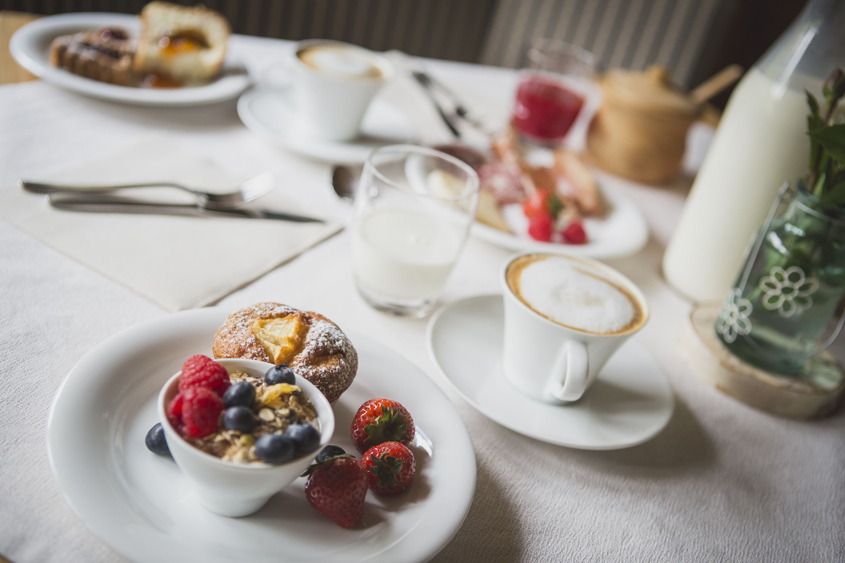 Un desayuno con platos de comida, una taza de café y un vaso de leche.