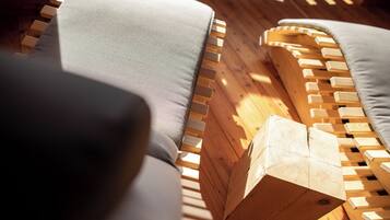 A wooden bench with a cushion, a wooden post, and a wooden floor.