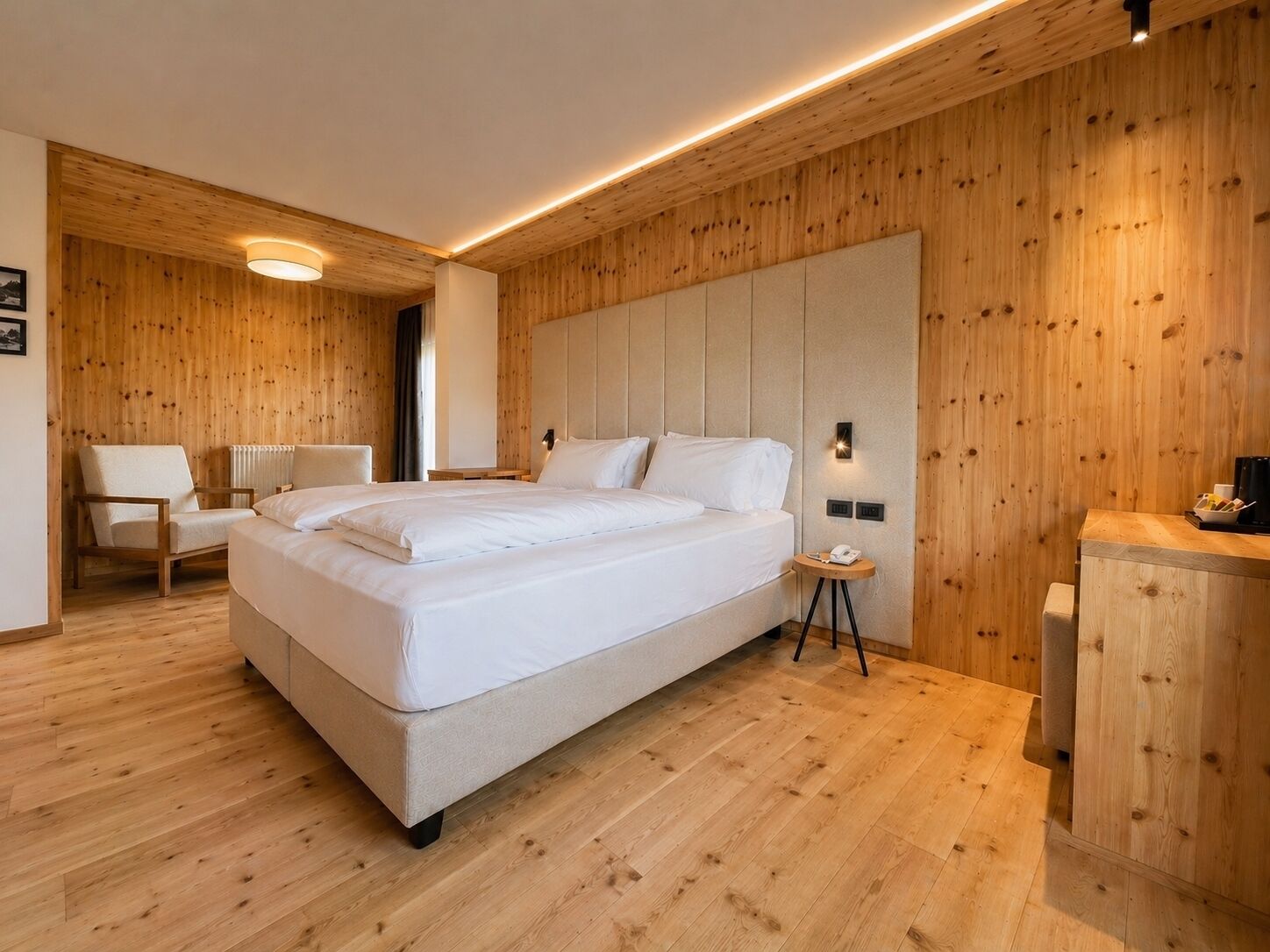 Een moderne slaapkamer met een groot bed, houten wanden en een klein nachtkastje.
