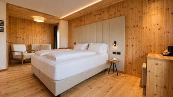 Een moderne slaapkamer met een groot bed, houten wanden en een klein nachtkastje.