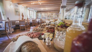 A breakfast buffet with various foods, including bread, pastries, fruits, and cheeses.