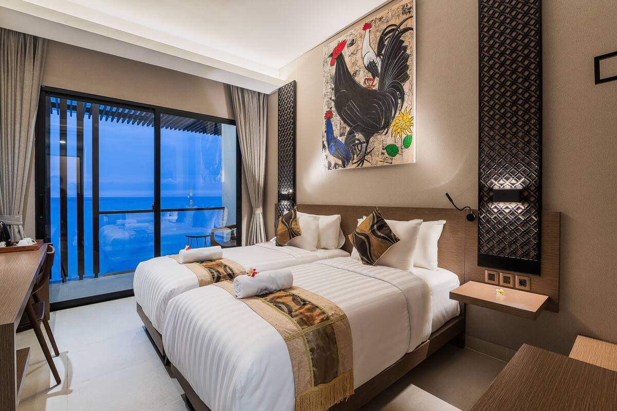 A hotel room with a large bed, a desk, and a view of the ocean.