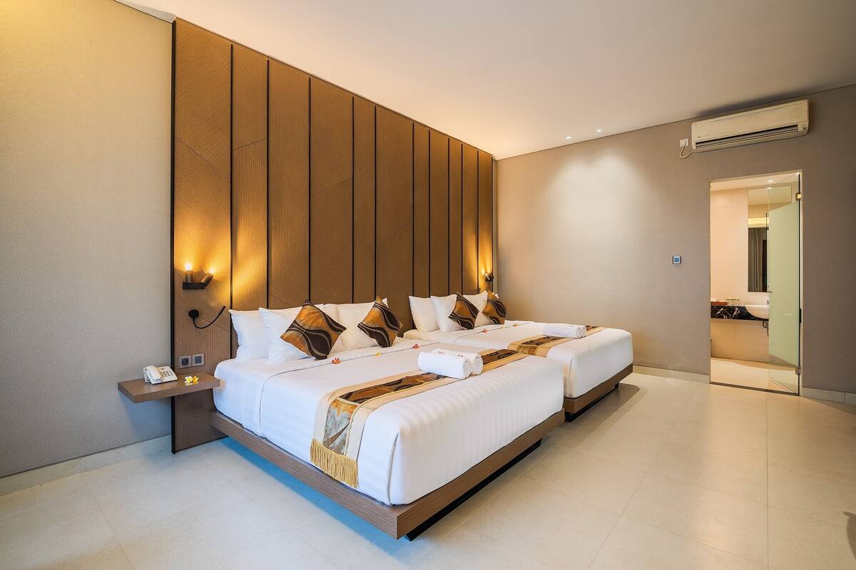 A modern hotel room with a large bed, bedside tables, and a bathroom visible through an open door.