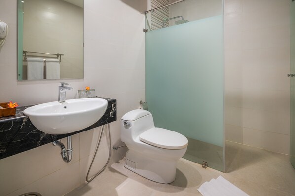 Une salle de bain moderne avec un lavabo blanc, des toilettes et une douche à parois de verre.