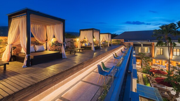 Ein Resort mit Außenbereichen, darunter eine Holzterrasse und ein überdachter Sitzbereich mit Baldachin.