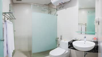 Un baño moderno con cabina de ducha de vidrio, inodoro blanco, lavamanos de mármol y estante de vidrio sobre el lavamanos.