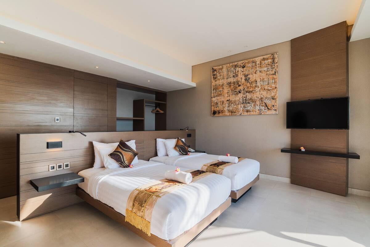 A modern hotel room with two beds, a TV, and a large abstract painting on the wall.