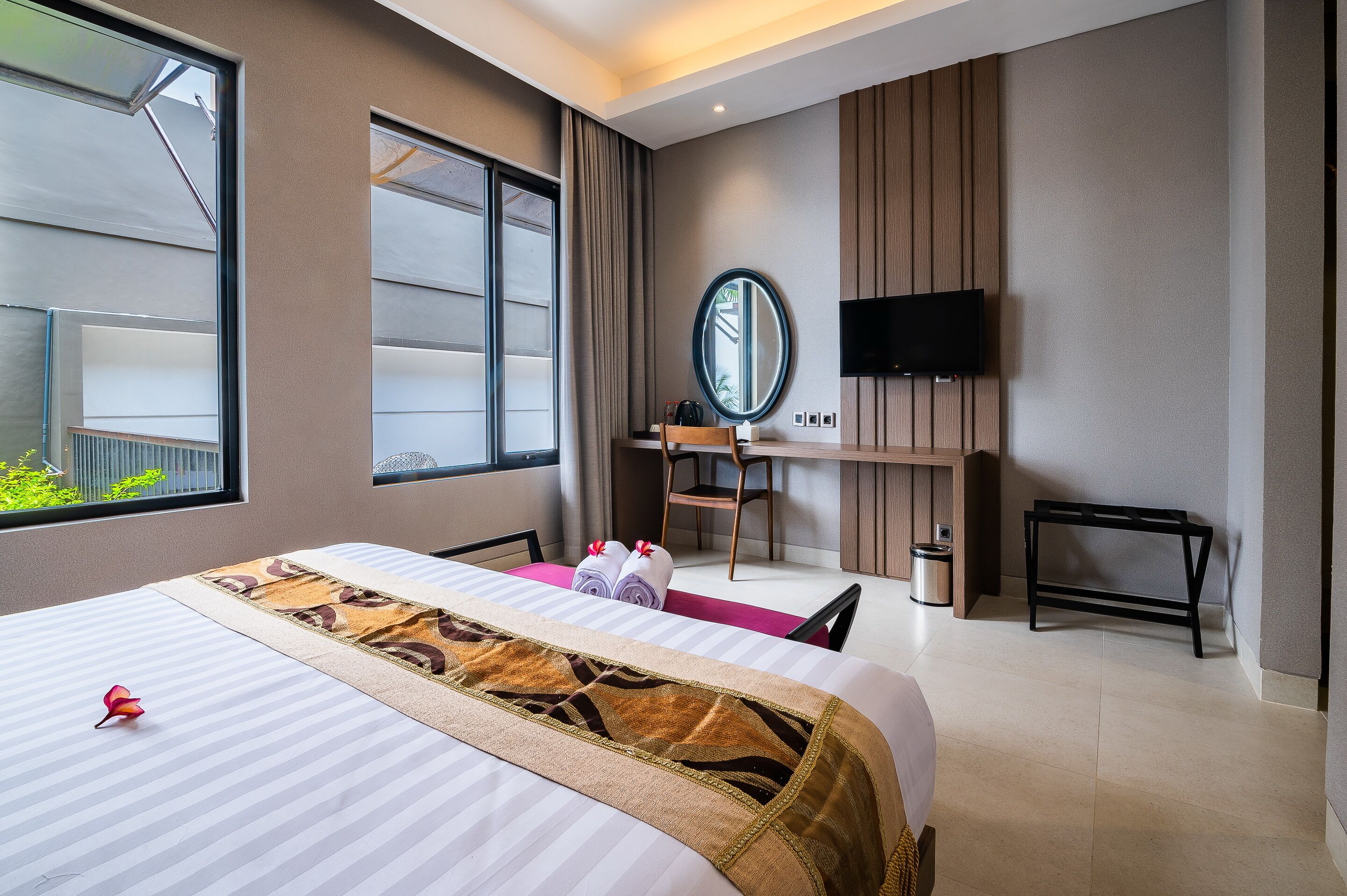 Habitación de hotel con una cama grande, un escritorio con silla, televisión y ventana con cortinas.
