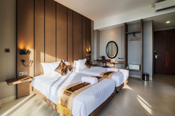 A modern hotel room with a large bed, wooden paneling, a mirror, and a small desk.