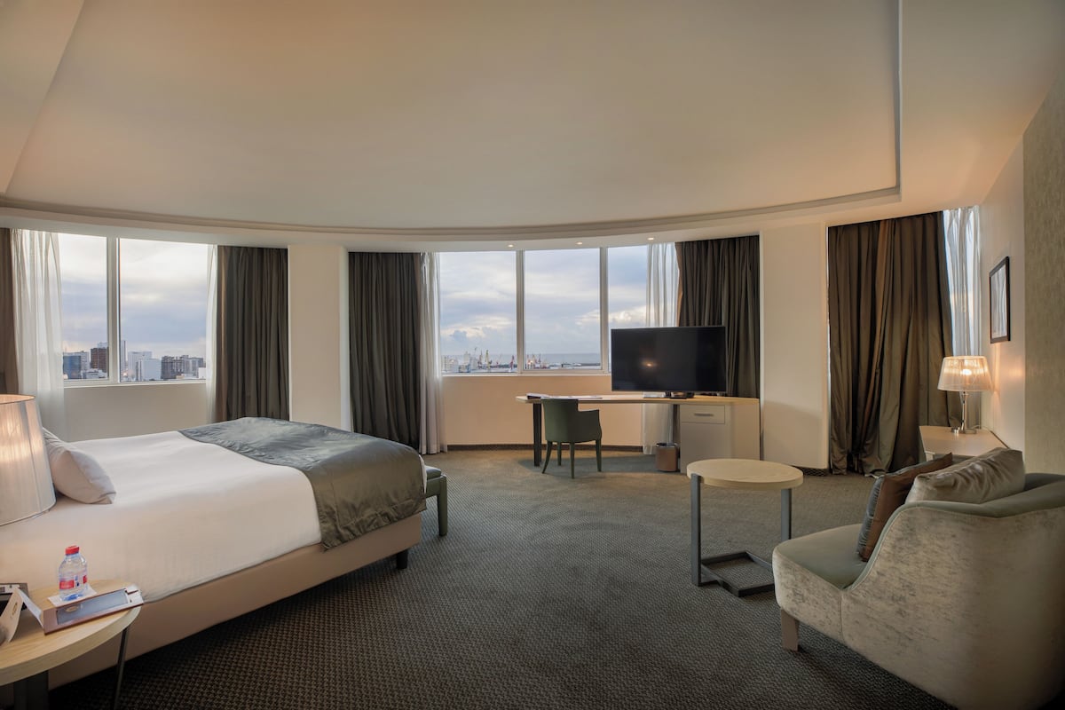 Une chambre d’hôtel avec un lit, un bureau, une télévision et une vue sur la ville.