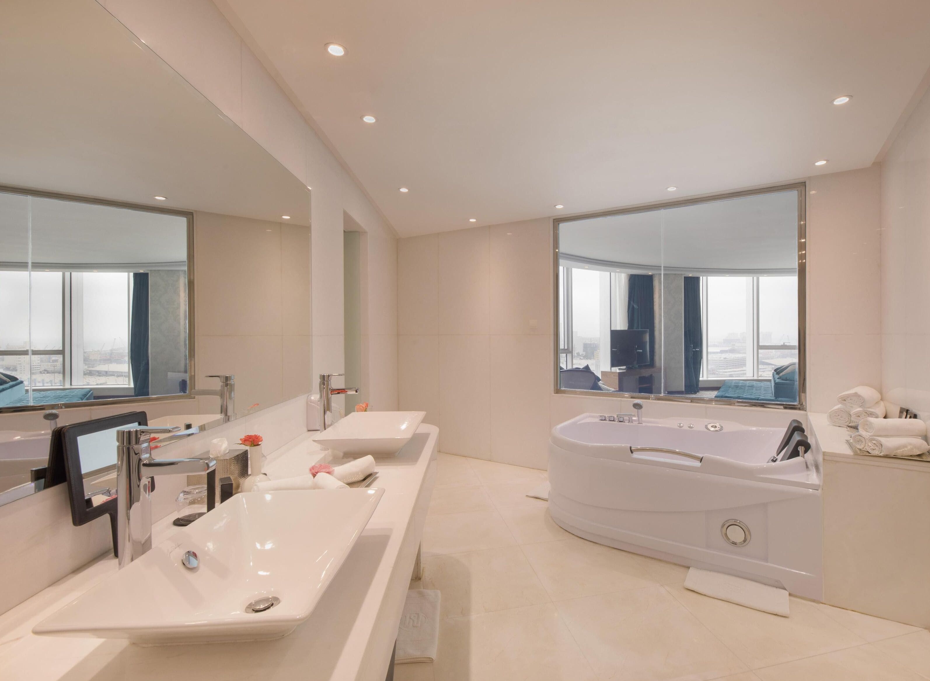 A modern bathroom with two sinks, a large bathtub, and a large mirror.