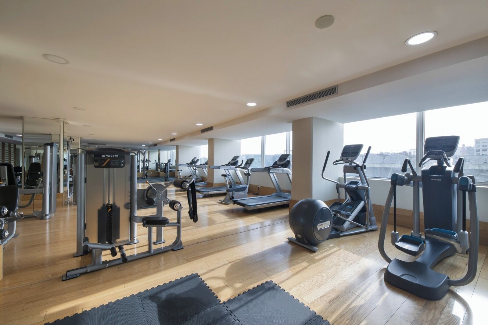 A gym with cardio machines, weight training equipment, and a large mirror.