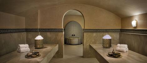 A spa area with two marble sinks, towels, and traditional lamps.