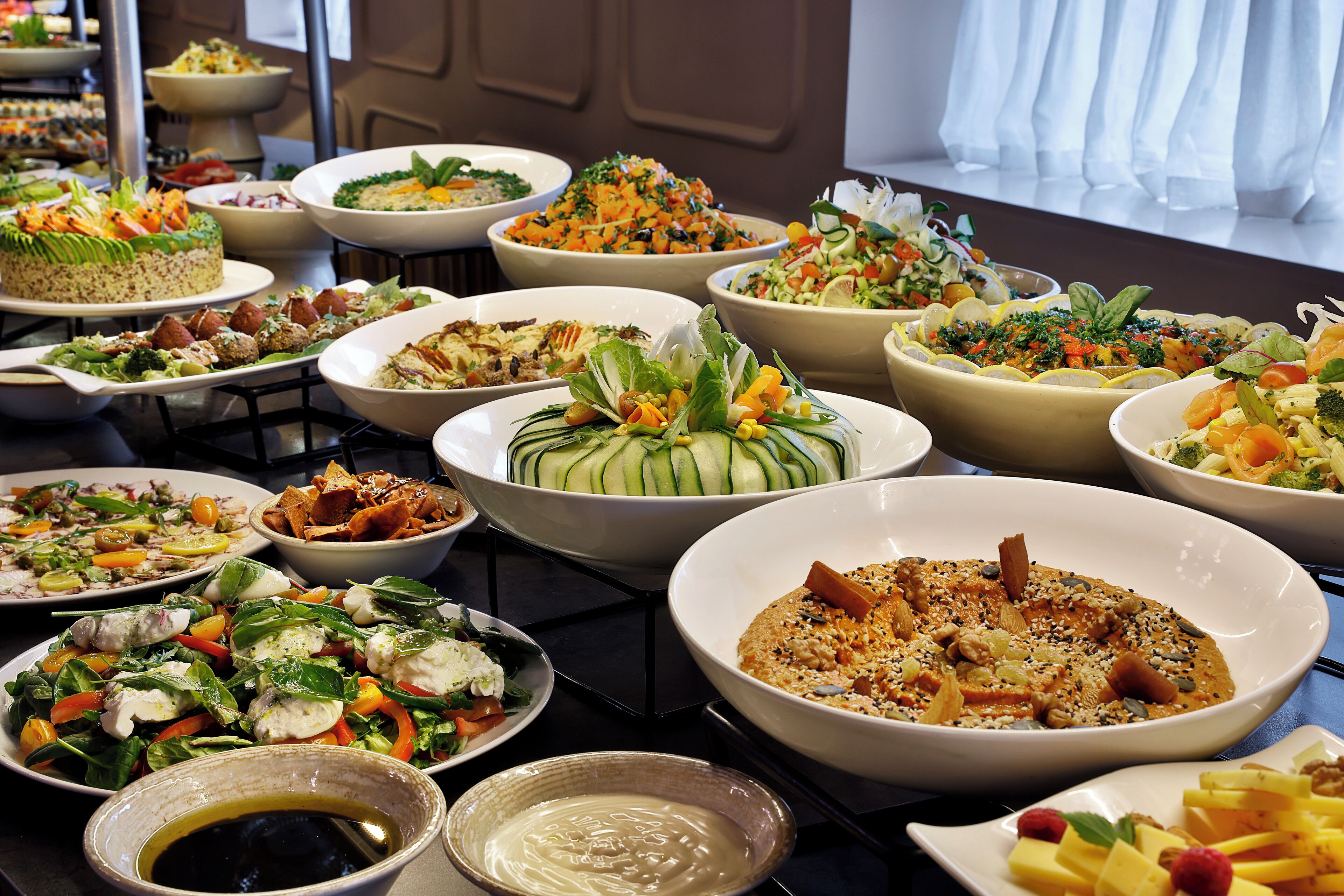 A buffet with various dishes including salads, vegetables, and desserts.