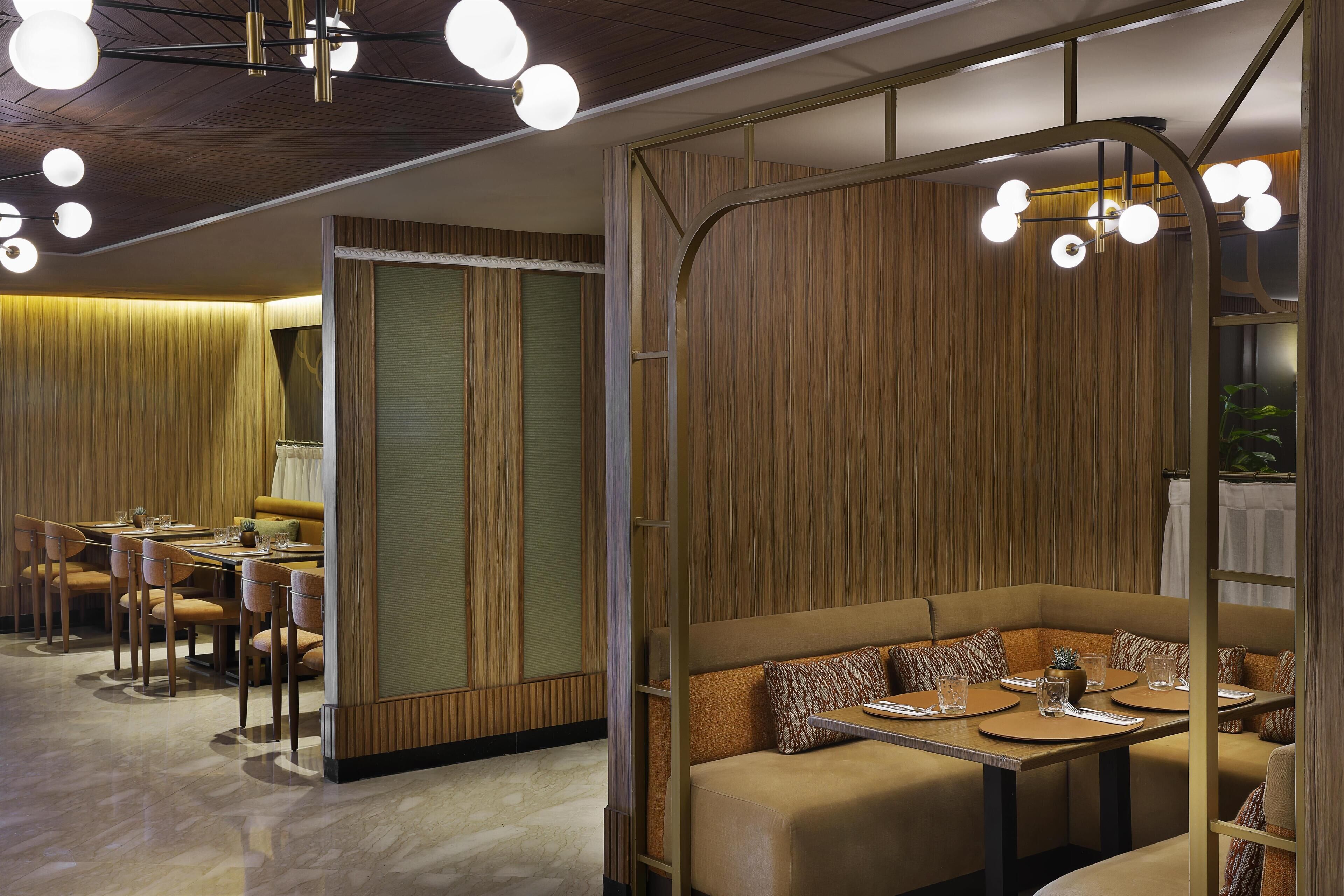Un espace de restauration moderne avec des murs recouverts de panneaux en bois, un aménagement comprenant des tables et des chaises, et un éclairage suspendu.