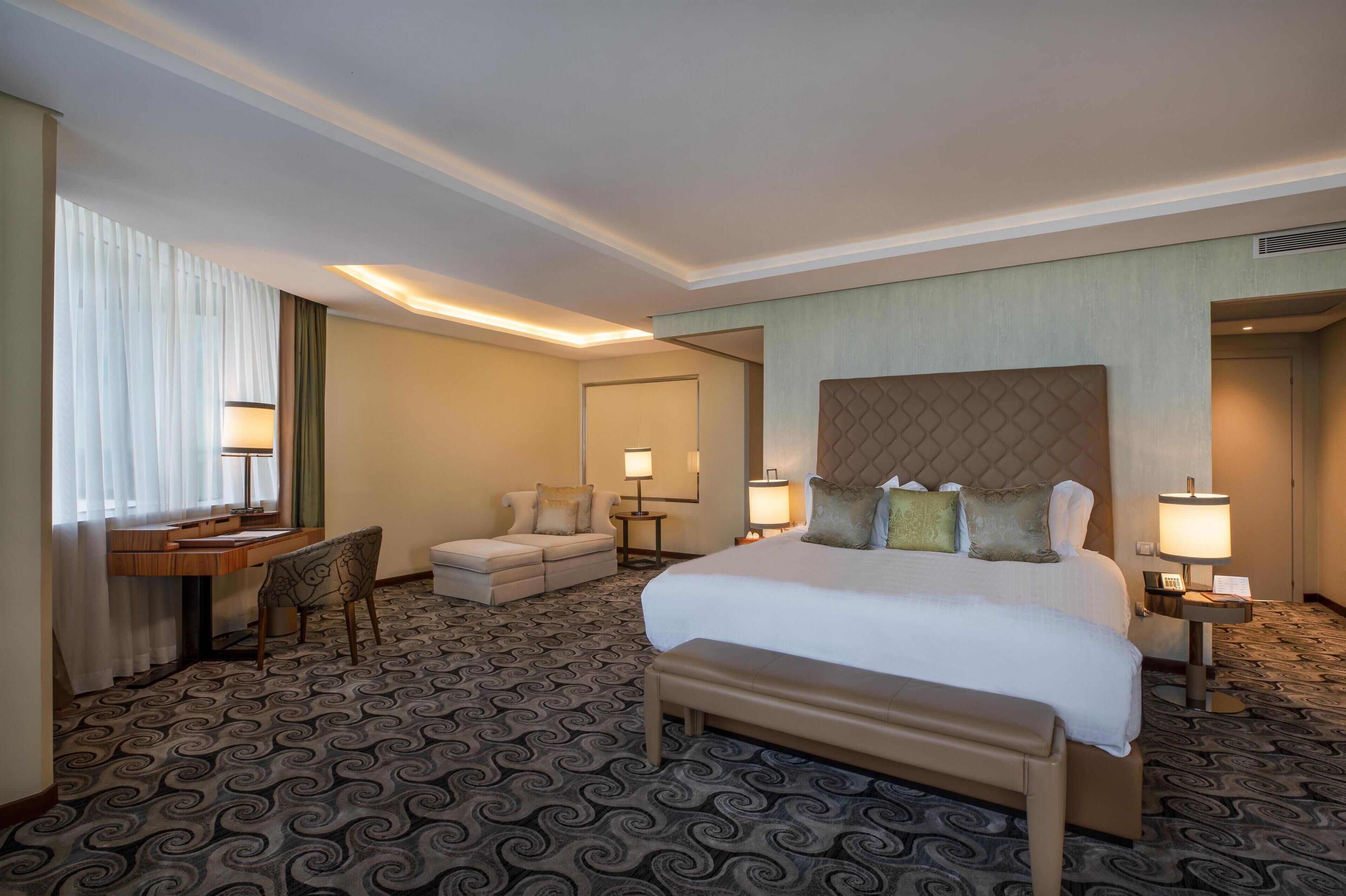 Une chambre d’hôtel avec un grand lit, un bureau, une chaise et un canapé.