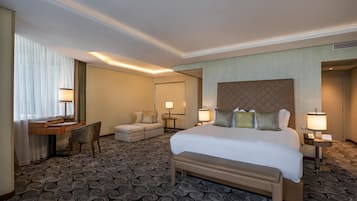 A hotel room with a large bed, a desk, a chair, and a sofa.