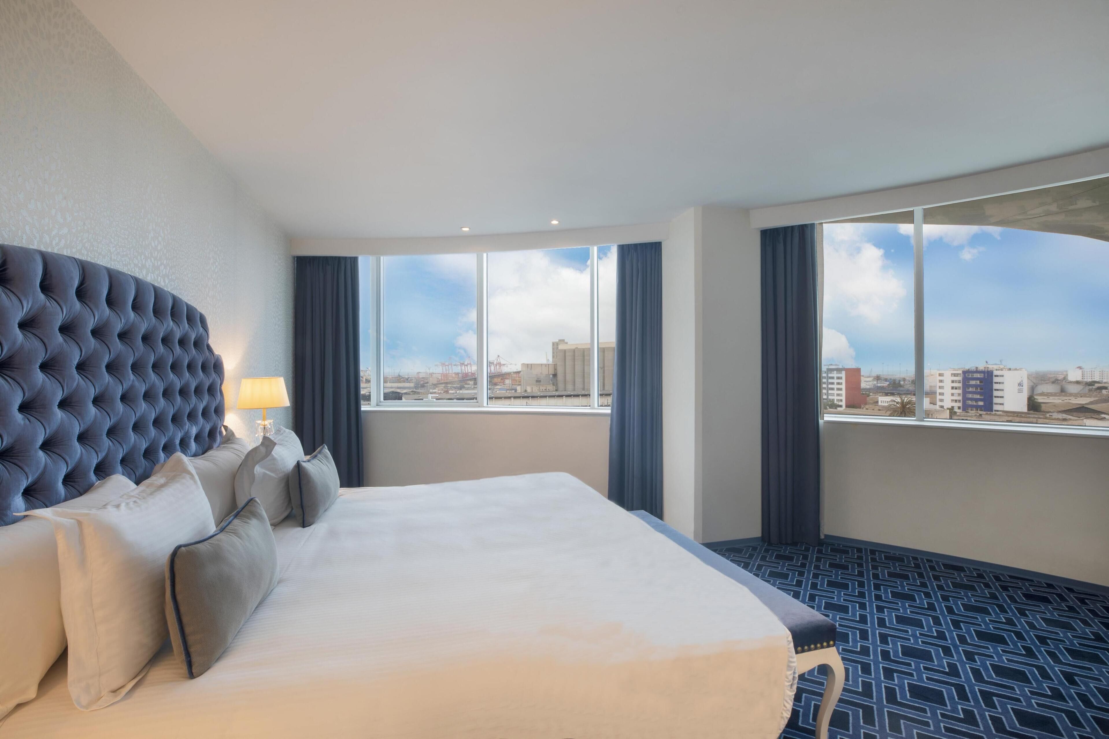 A hotel room with a large bed, a view of the city, and a modern design.