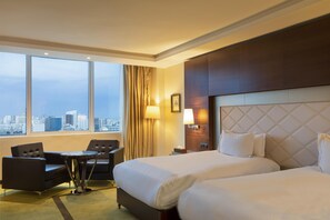 A hotel room with a large bed, two armchairs, a small table, and a city view through large windows. - DoubleTree by Hilton Casablanca City Centre (Casablanca)