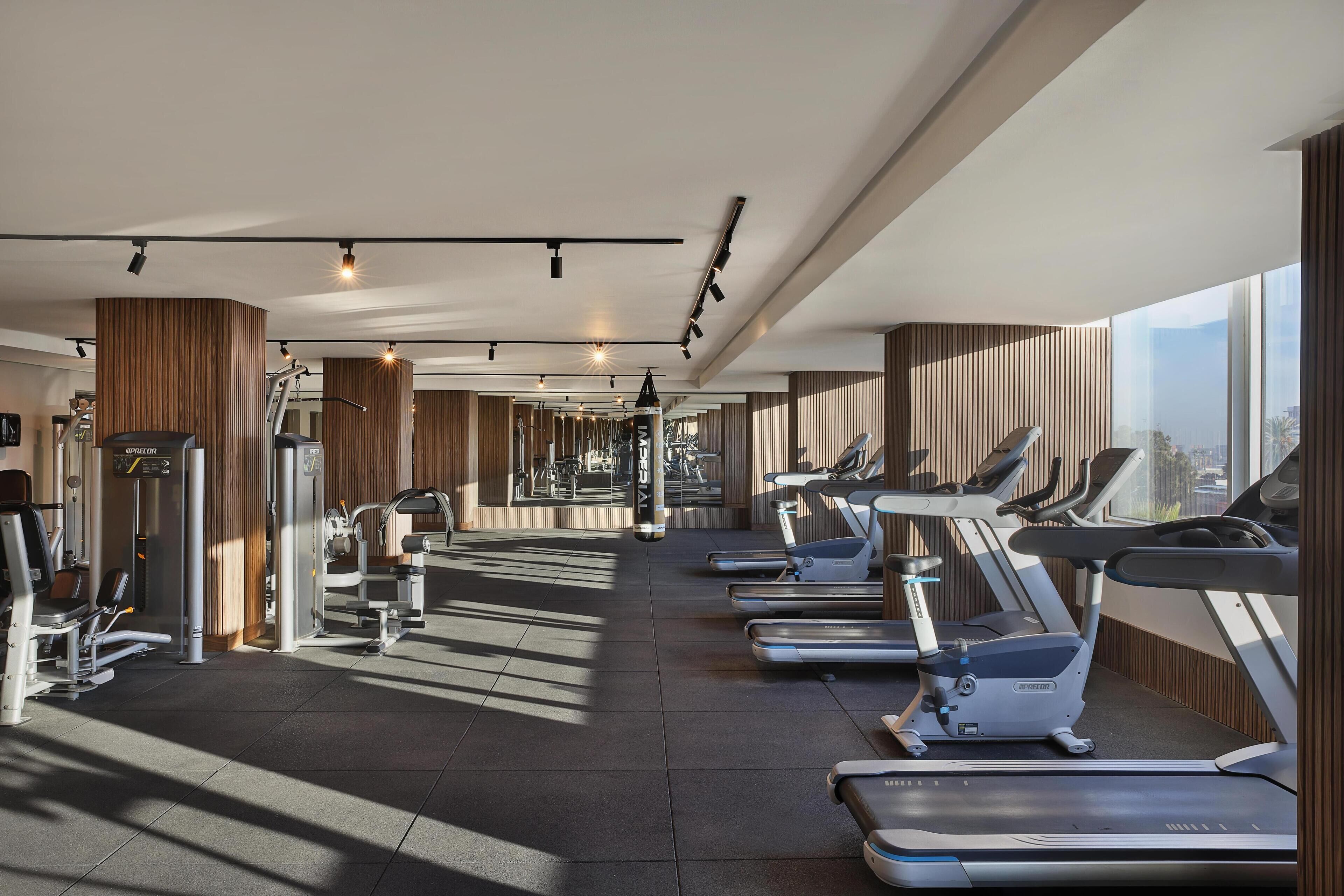 Ett modernt gym med löpband, styrketräningsmaskiner och en stor spegel.
