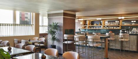 A restaurant with a bar area, tables, chairs, and potted plants.