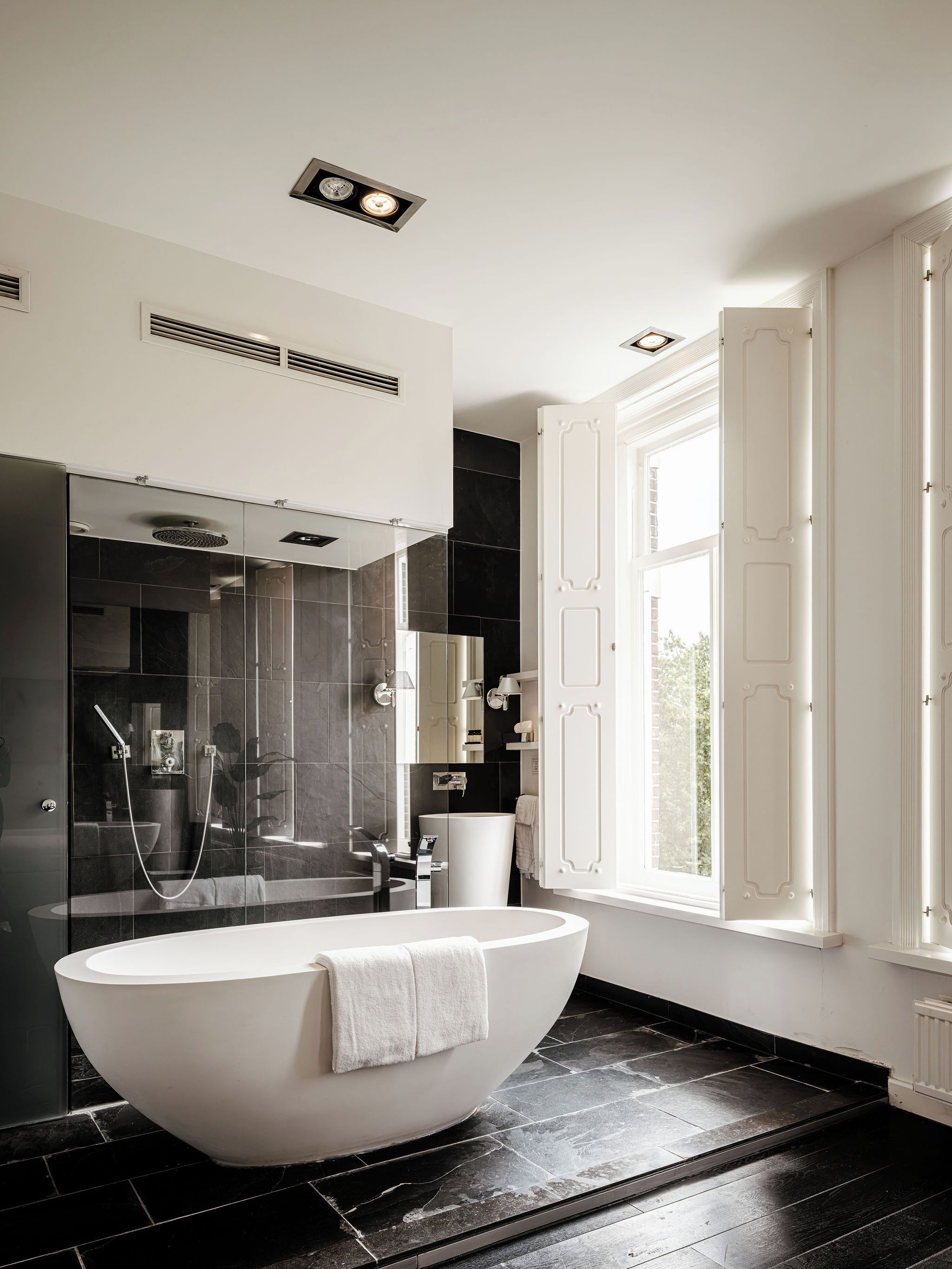 Une salle de bain moderne avec une baignoire sur pieds, une douche à parois de verre et une grande fenêtre.