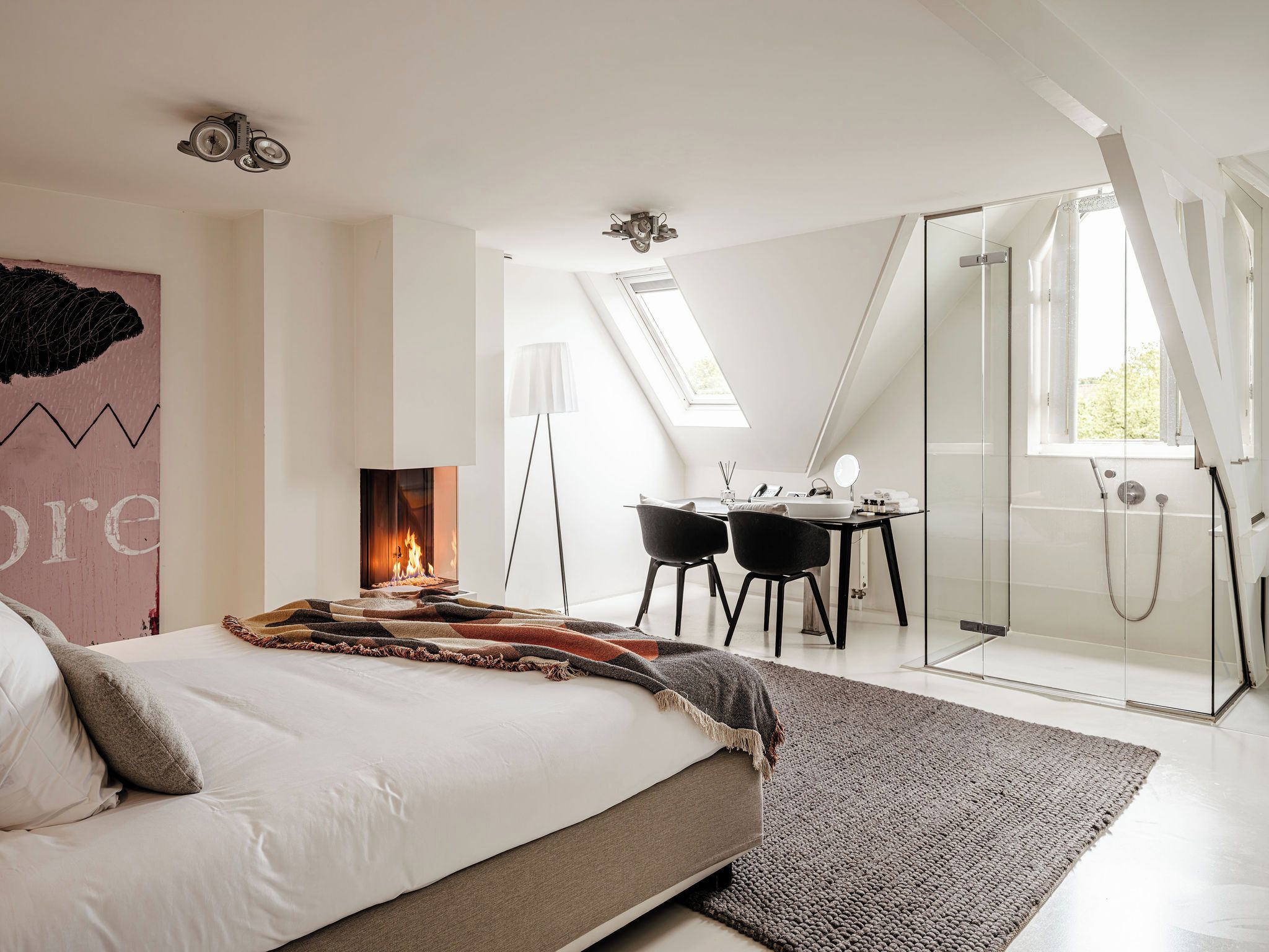Un dormitorio moderno con cama, escritorio y ducha de vidrio.