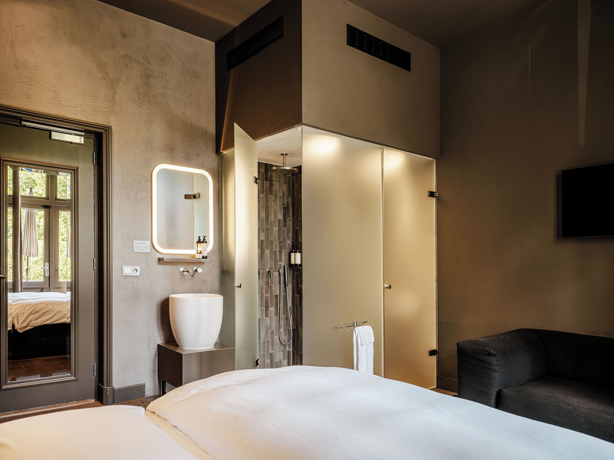 Une chambre d’hôtel avec un grand lit, une salle de bain avec douche, un lavabo et un miroir.