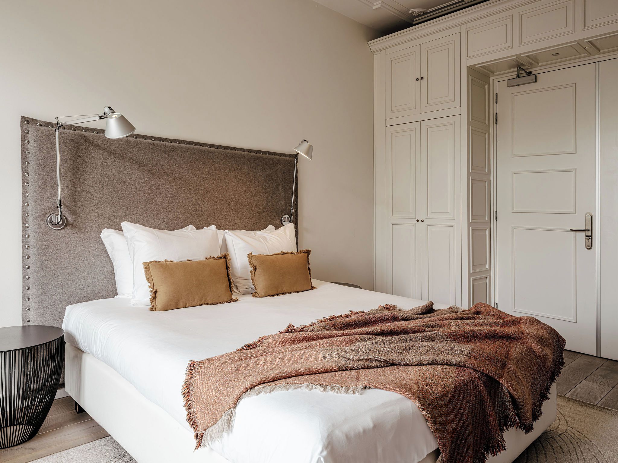 Quarto com cama, almofadas, manta, mesa de cabeceira e guarda-roupa.
