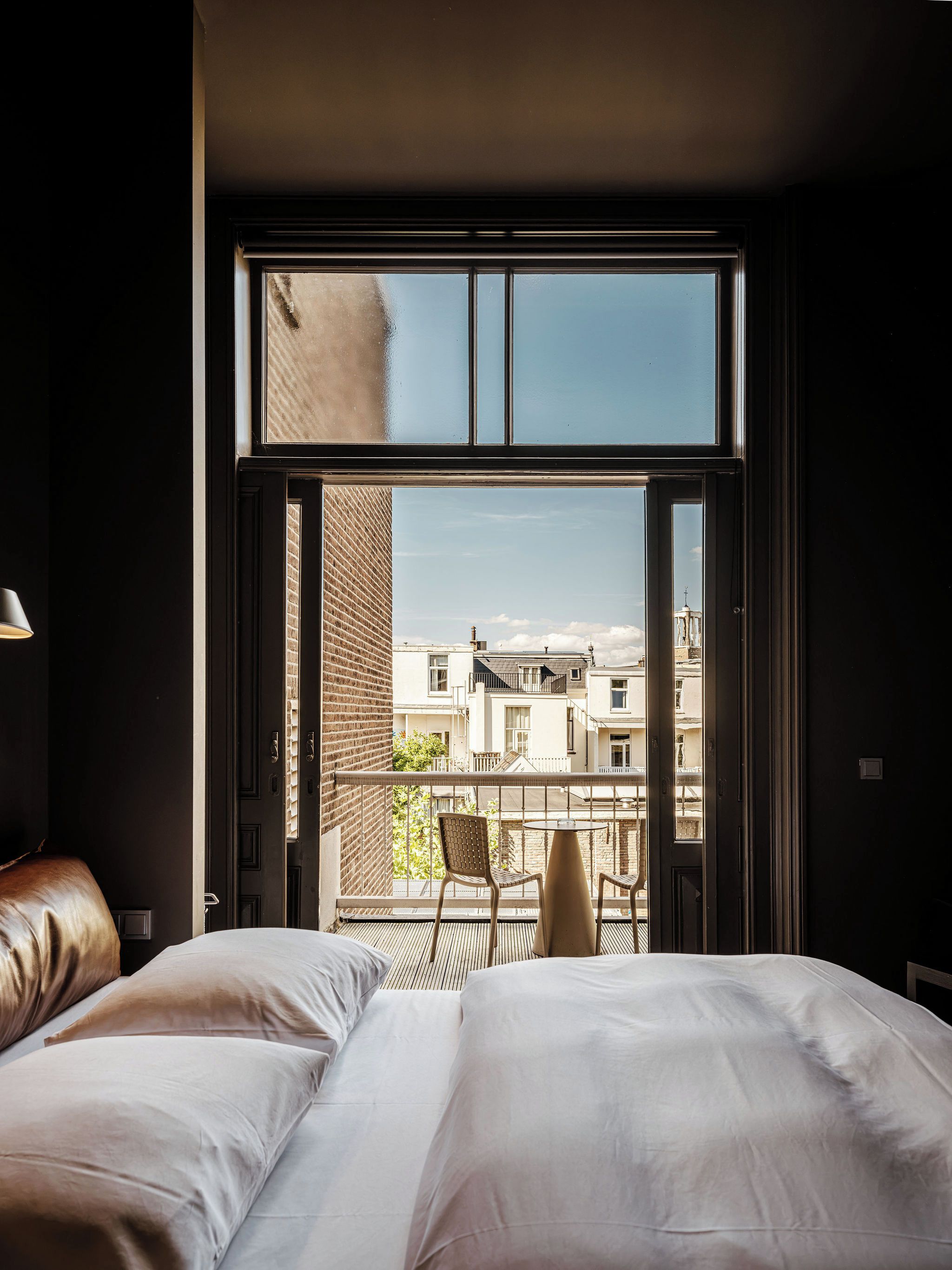 Ein Schlafzimmer mit großem Fenster, einem Bett, einem Sessel und einem Tisch.