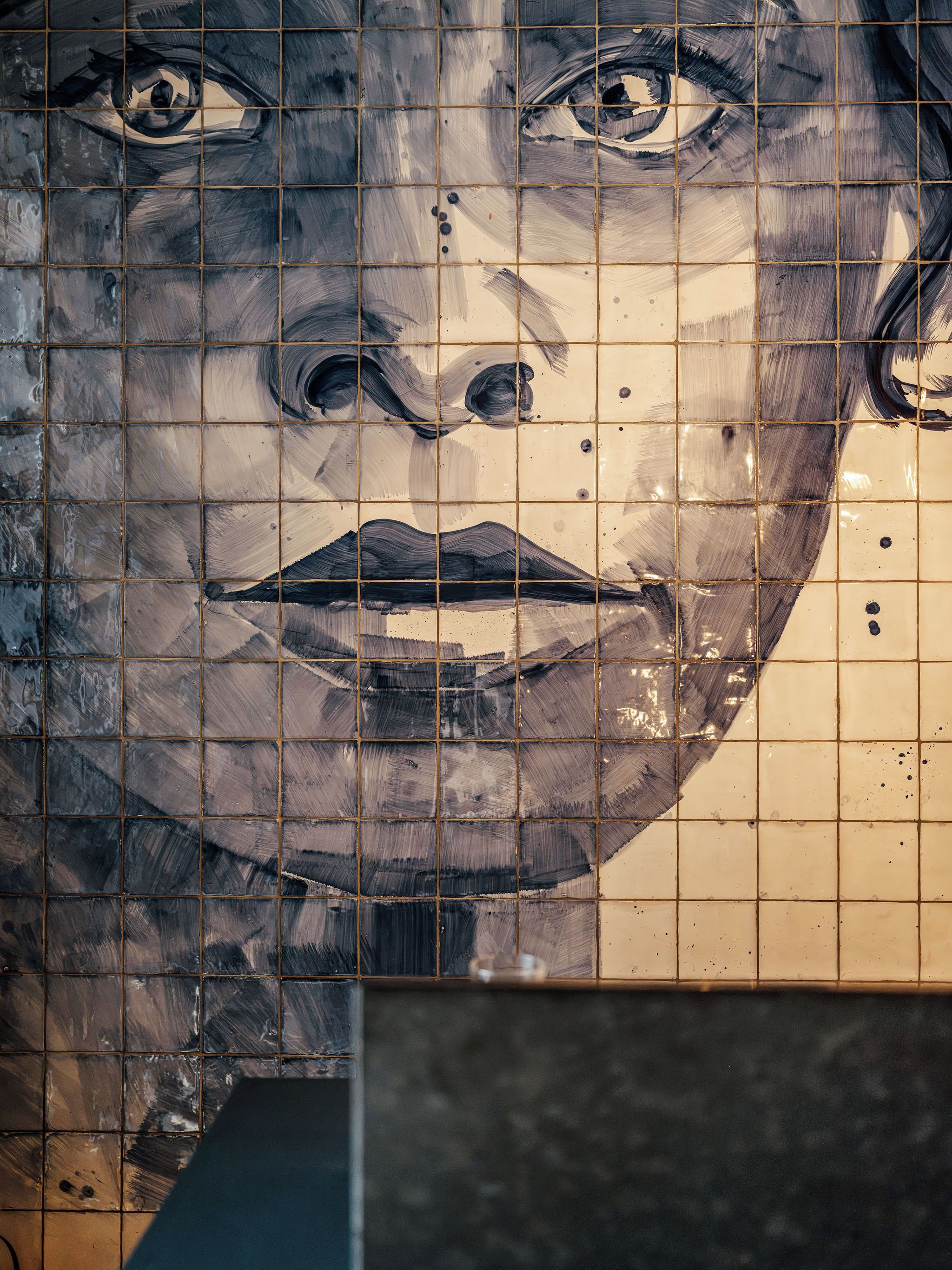 A tiled wall with a grid pattern and a partial view of a room with a dark floor.
