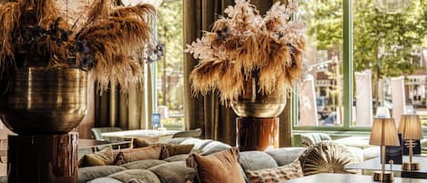 Un rincón acogedor con sofá y sillones, una mesita de centro y jarrones decorativos con plantas secas.
