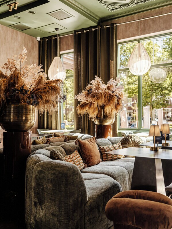 Un rincón acogedor con sofá y sillones, una mesita de centro y jarrones decorativos con plantas secas.