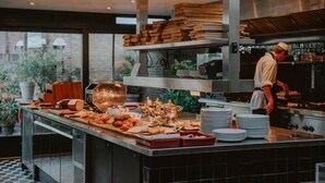 A modern kitchen with a buffet setup, including various food items and stacked plates. - Boutique Hotels MANNA & Blue (Nijmegen)