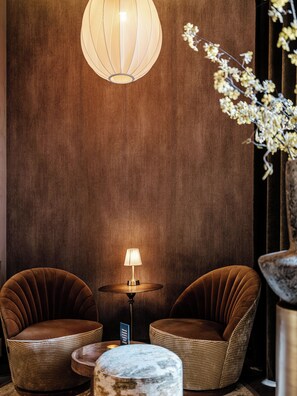 A room with two brown upholstered chairs, a small round table, a floor lamp, and a hanging light fixture. - Boutique Hotels MANNA & Blue (Nijmegen)