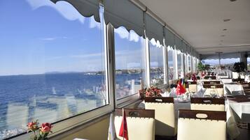 Enjoy meals with a view of the ocean from this dining area, featuring tables, chairs, and a wavy ceiling.