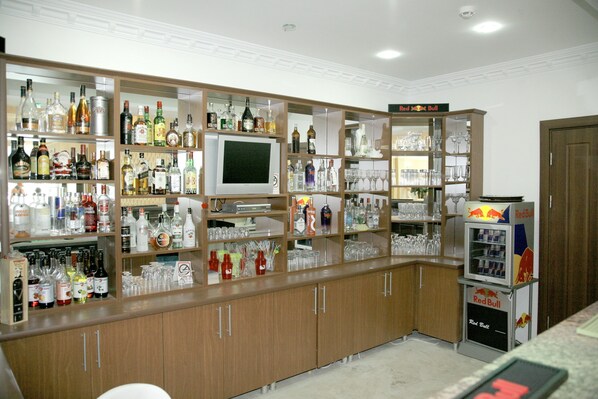 Een bar met flessen drank, glazen en een Red Bull automaat.